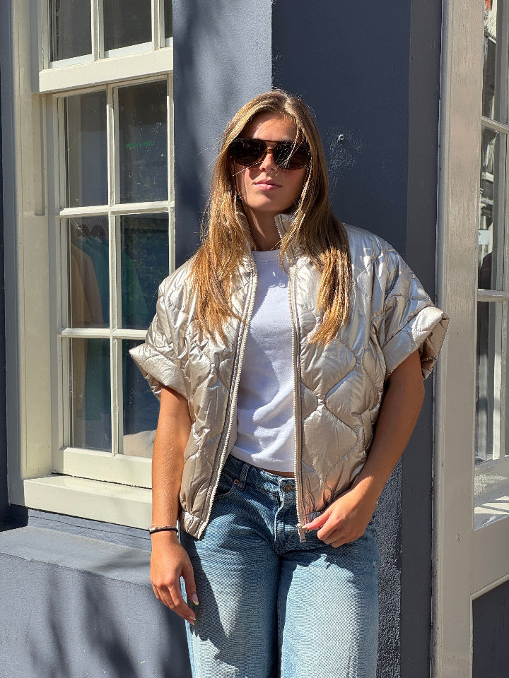 Doorgestikte bodywarmer metallic met rits en zakken.